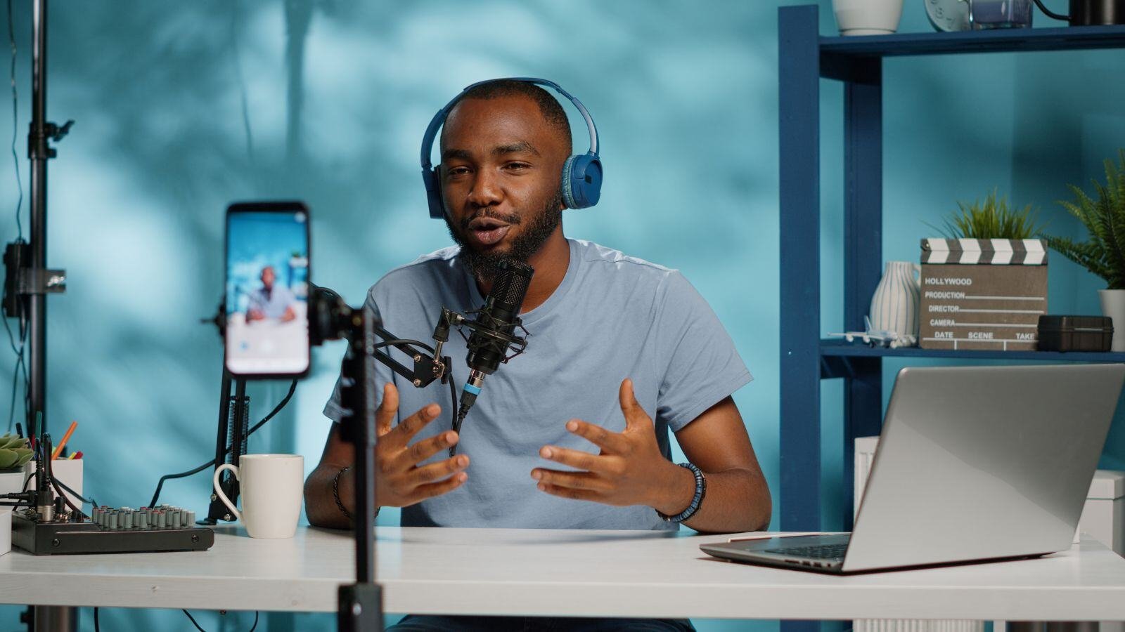 Man recording himself on his phone while speaking in front of a microphone